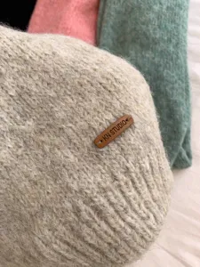 Nahaufnahme der weichen Strickschal-Textur mit schickem Leder-Markenlabel und kuscheligem Stoff.