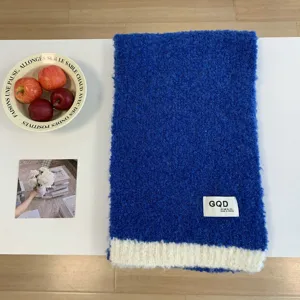 Blauer Strick-Wollschal im Winter mit weißem Kontrastsaum und gemütlichem Markenetikett