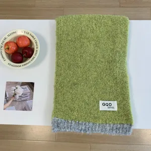 Detailansicht eines kuscheligen Wollmischgewebe-Farbblock-Strickschals in Grün und Grau.