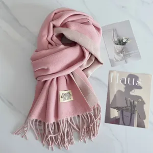 Detailansicht des rosa-beigen Wendeschals aus Kunstkaschmir mit Fransen und Etikett.
