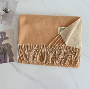 Detailaufnahme des wendbaren Kaschmir-Gefühl Winterschals mit eleganten Fransen und Label.