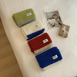 Nahaufnahme von kuscheligen, farbblockierten Strickschals in verschiedenen Tönen ordentlich.
