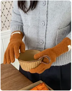Nahaufnahme der braunen Strickhandschuhe aus Wolle mit feiner melierter Textur.
