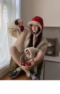 Gemütliche Winter Mütze mit Ohrenklappen im warmen Innenbereich mit Apfel Requisiten.