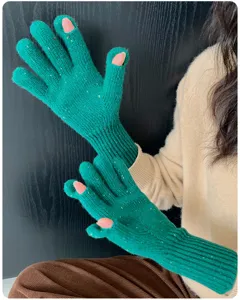 Nahaufnahme der langen grünen Damen-Strickhandschuhe mit bunten Punkten im Detail.