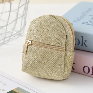 Close-up detail shot of sparkling gold mini backpack coin purse pendant with metal zipper closure.
