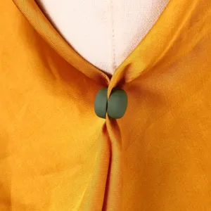 Gros plan de la boucle d'écharpe magnétique verte fixant le châle ou le foulard en tissu.