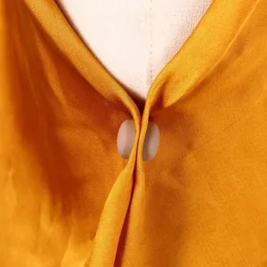 Gros plan detail du tissu de foulard en soie jaune fixe avec un clip aimante rond accessoire.