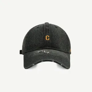 Detailansicht der schwarzen Jeans-Baseballkappe mit ausgefranster Krempe und orangefarbenem C.