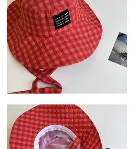 Primo piano sui dettagli del cappello da pescatore a quadri rossi e arancioni.