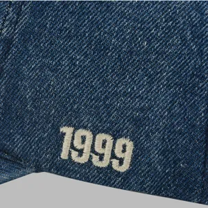 Nahaufnahme einer dunkelblauen Jeansstoff-Baseballkappe mit weißer 1999-Stickerei