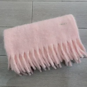 Detailansicht des weichen, rosa flauschigen Winterschials mit dicker Fransenstruktur.