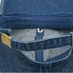 Nahaufnahme des Denim-Baseballkappen-Rückengurts mit Bronzemetall-Schnalle und Innendetail.