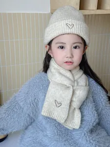 Close-up detail of kids knit beanie hat and scarf set with cute heart embroidery, warm.
