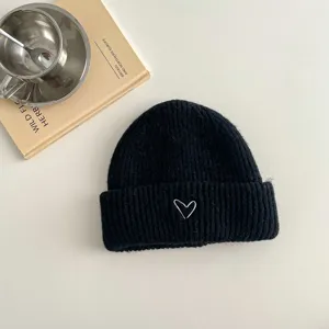 Detailed view of the black kids knitted beanie featuring a cute white embroidered heart pattern.