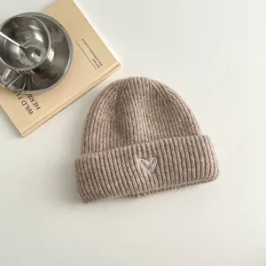 Detailed close-up of khaki kids knit beanie featuring a cute white heart embroidery.