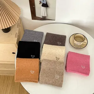 Children knitted scarf details showing various solid color winter scarfs with cute heart embroidery.