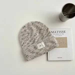 Vista detallada de un cómodo gorro de punto con textura de lana jaspeada y pequeña etiqueta.