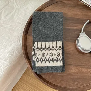 Cozy dark grey knitted scarf with geometric patterned border, soft winter warmth accessory.