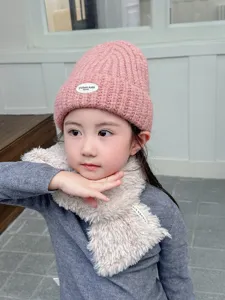 Gros plan détaillé du bonnet en tricot rose douillet et de l'écharpe moelleuse enfants.