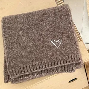 Brown knitted winter scarf detail featuring a cute white heart embroidery pattern.