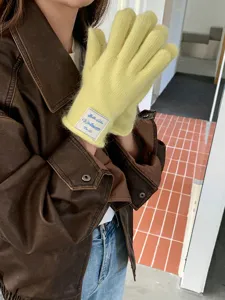Primo piano dettagliato di guanti in maglia touch screen gialli indossati con giacca di pelle.