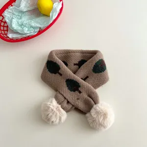 Children knitted cross scarf with cute pom poms detail and tree pattern design for winter.