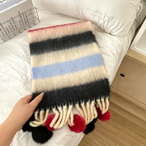 Nahaufnahme des bunten gestreiften Kinderwinterschals mit niedlichen Bommel-Quasten.