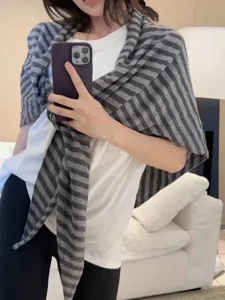 Detailed view of women's grey striped wool triangular scarf, cozy knit wrap for autumn winter.