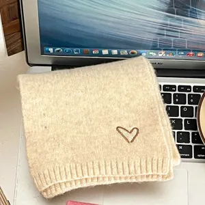 Close-up of a soft beige knitted children scarf featuring a cute brown embroidered heart detail.