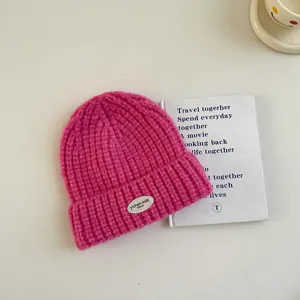 Gros plan détail d'un bonnet en tricot rose vif pour enfants avec un petit patch blanc de marque.