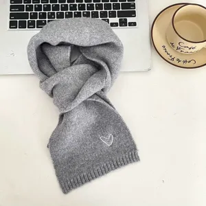 Grey knit scarf detail showing cute white heart embroidery, soft winter accessory close-up