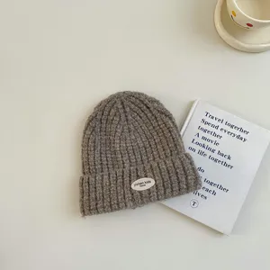 Bonnet en tricot marron confortable pour enfants avec patch tissé, idéal pour l'hiver.