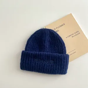 Dettaglio berretto in maglia blu scuro, soffice con ricamo gatto, abbigliamento invernale.