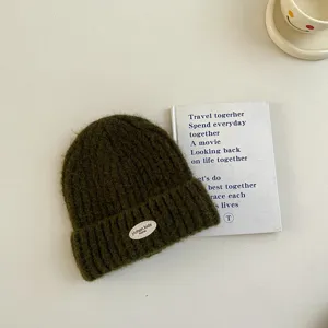 Gros plan détail du bonnet en tricot vert foncé pour enfants avec écusson, texture.