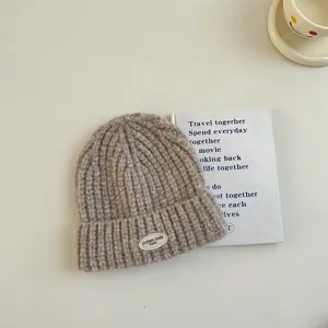 Gros plan d'un bonnet en tricot douillet pour enfants en couleur kaki avec écusson.