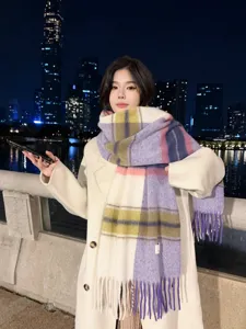 Detailed shot of a stylish color-block plaid tassel scarf worn by model outdoors at night.