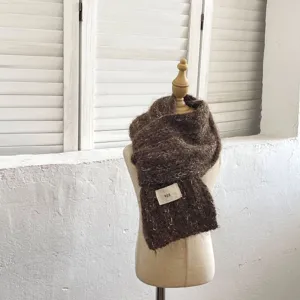 Vista detallada de la bufanda de punto esponjoso marrón para niños con etiqueta de marca.
