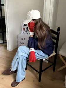 Detailed view of cozy red knit winter gloves featuring white cuffs and stylish button in scene.