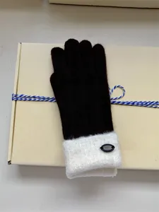 Close-up detail of winter knit gloves in dark brown with cozy white furry cuff and chic logo.