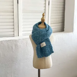 Vista detallada de una suave bufanda de punto azul con etiqueta, perfecta para días fríos.