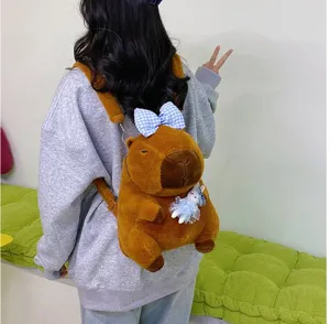 Linda mochila de peluche de carpincho marrón con lazo azul, usada por una modelo.