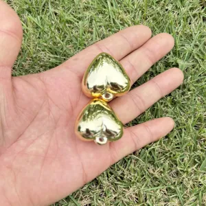 Detailed view of two shiny gold heart-shaped charms held in hand for DIY jewelry