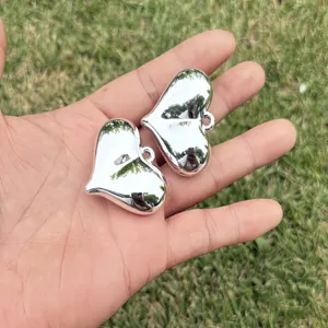 Close-up of two shiny silver heart pendants held in hand for DIY jewelry making