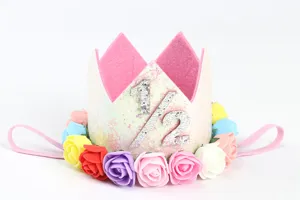 Detalle de una diadema de corona con purpurina, rosas coloridas y el número 1/2