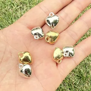 Detail of polished gold and silver heart-shaped pendants on palm for DIY jewelry