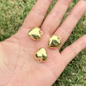 Detailed view of polished gold heart pendants held in hand for DIY jewelry making