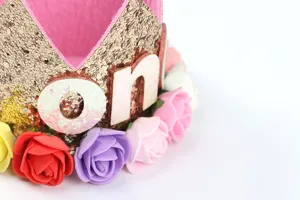 Primer plano detallado de corona de cumpleaños dorada con rosas de colores para bebés