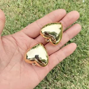 Macro view of golden CCB heart-shaped pendants with smooth metallic finish on palm