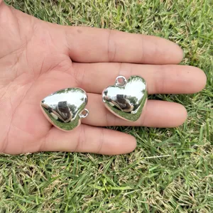 Detail of glossy silver heart charms held in hand for DIY jewelry making